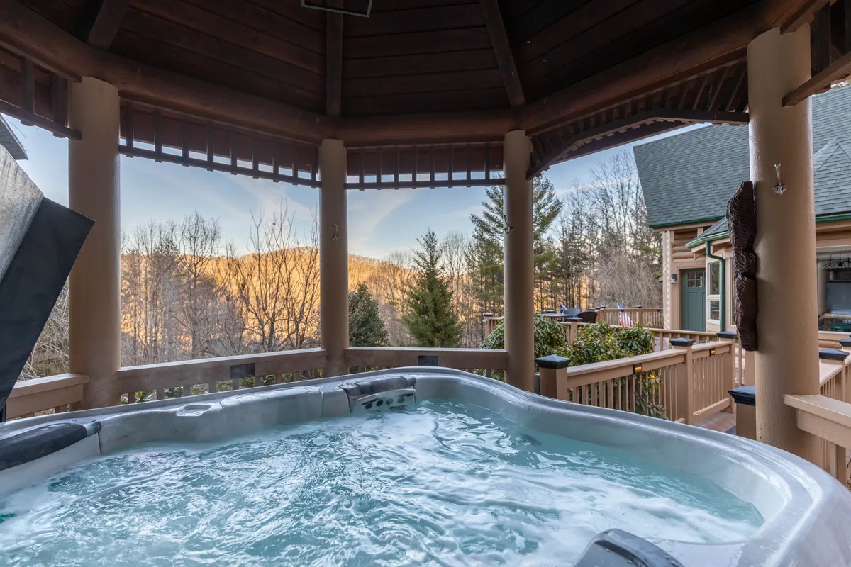 This image centers on an outdoor hot tub overlooking scenic mountain views, set against a rustic wooden structure. The atmosphere is calm, perfect for soaking in the high country landscape with family or friends.