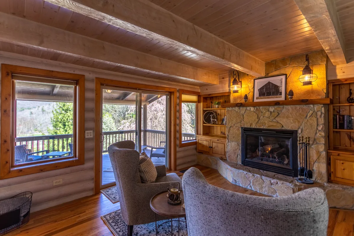 A cozy reading room with plush armchairs positioned by a warm fireplace, large windows letting in daylight, and wooden shelves lined with books. The ambiance is both relaxing and intimate, ideal for retreating with a book or enjoying a hot beverage.