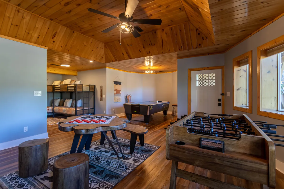 A lively recreation room featuring a foosball table, pool table, checkers game on a game table, and wooden stools. The space exudes a playful and relaxed mood, designed for group activities and fun gatherings.