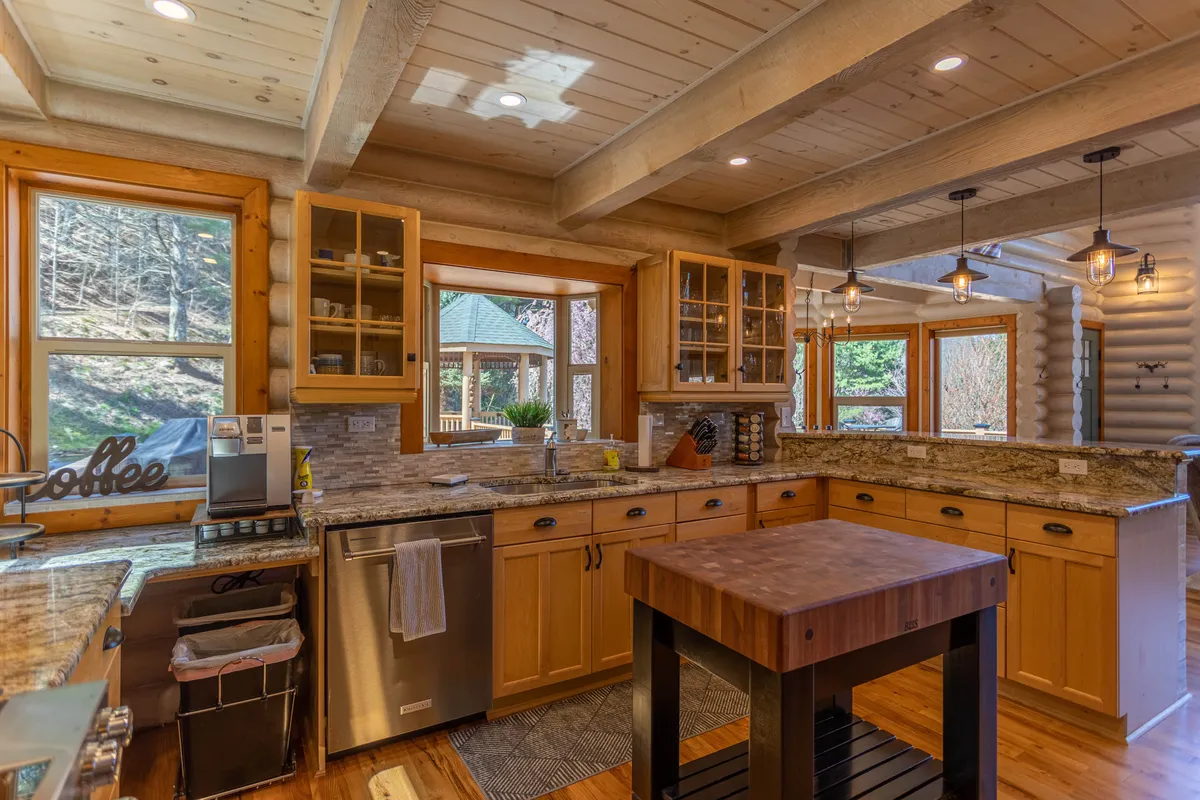 A beautifully designed kitchen featuring a prominent island, cozy wooden cabinetry, large windows offering scenic views, and gleaming granite countertops. The space is perfect for cooking, entertaining, and family gatherings, inviting both casual breakfast moments and festive cooking sessions.
