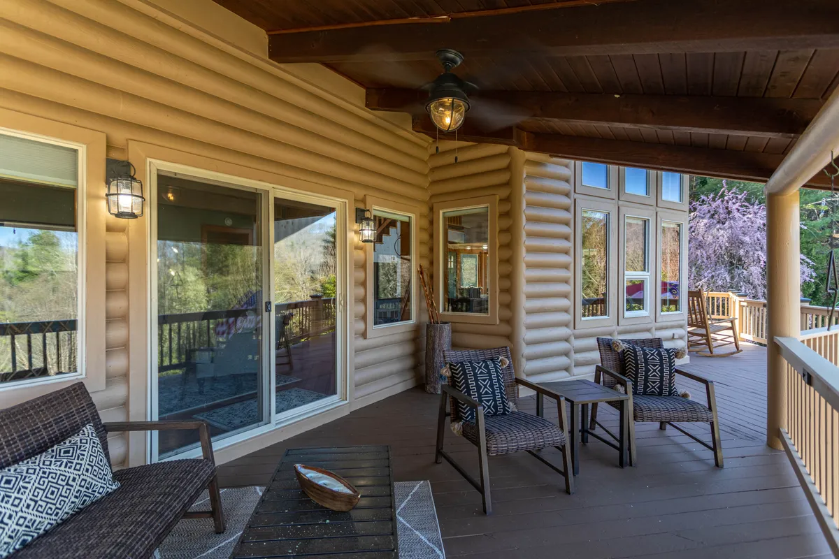 A tranquil exterior seating area with wooden railings, comfortable chairs, large windows, and decorative lanterns. The deck is enveloped by greenery and offers a peaceful spot for wildlife watching, reading, or sharing drinks as the sun sets.